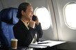 © Prathankarnpap - Successful senior businesswoman passenger talking on mobile phone while sitting in airplane cabin near windows