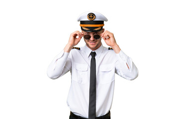 Wall Mural - Airplane pilot man over isolated background with glasses and surprised