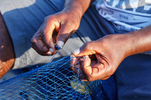Hands Of A Fisherman Mending A Torn Net