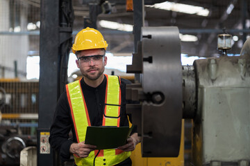 Male engineer worker working and inspecting parts quality of lathe machine in industry factory, wearing safety uniform, helmet. Male technician worker maintenance parts of machine in workshop