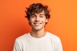 © Markus Schröder - Close-up portrait photography of a satisfied boy in his 20s wearing a casual t-shirt against a bright orange background. With generative AI technology