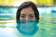 Beautiful woman immersing in water in a private swimming pool looking at camera