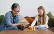 Happy grandmother and granddaughter play chess on the sofa.
