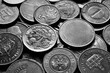 A fragment of a coin pile. Coins of different countries, black and white image. Background.