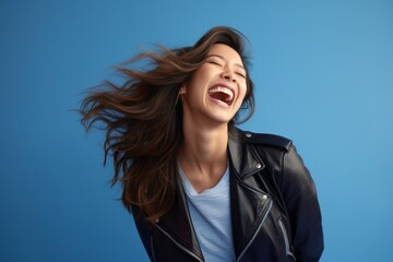 Canvas Print - Lifestyle portrait photography of a joyful girl in her 30s wearing a sleek bomber jacket against a soft blue background. With generative AI technology