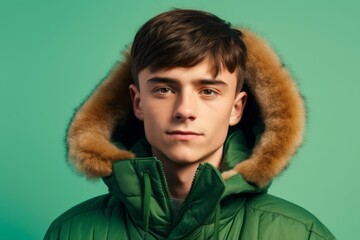 Poster - Close-up portrait photography of a beautiful boy in his 30s wearing a warm parka against a pastel green background. With generative AI technology