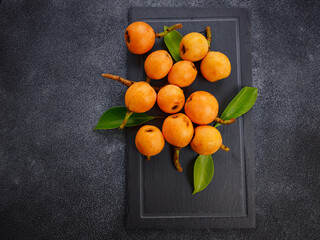 Loquat Medlar fruit isolated on dark table background. Also called as Nispero and Eriobotrya japonica. Close up.