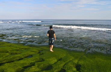 Wall Mural - A man standing and taking photos at Balangan beach.