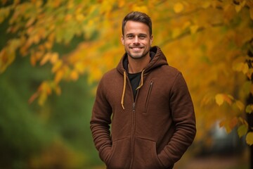Wall Mural - Lifestyle portrait photography of a satisfied boy in his 30s wearing a comfortable hoodie against an autumn foliage background. With generative AI technology