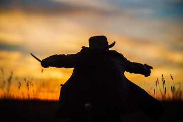 Demon and vampire hunter silhouette is fighting. A man with a katana and a revolver. Dramatic sky in the background. Fantasy and halloween concept