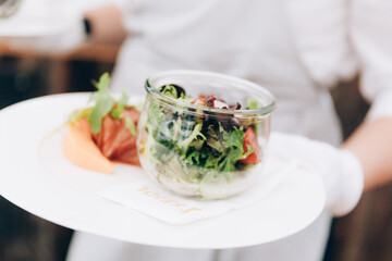 Serving plates with green salad in restaurant.