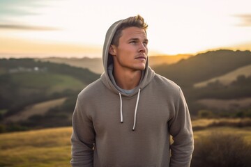 Wall Mural - Environmental portrait photography of a glad boy in his 30s wearing a stylish hoodie against a rolling hills background. With generative AI technology