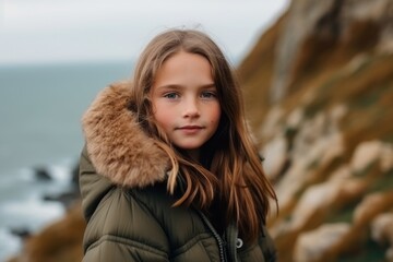 Wall Mural - Medium shot portrait photography of a glad kid female wearing a cozy winter coat against a dramatic coastal cliff background. With generative AI technology