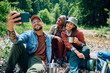 © Drazen - Happy group of friends taking selfie with cell phone while camping in nature.