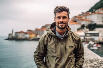 Wall Mural - Urban fashion portrait photography of a glad boy in his 30s wearing a lightweight windbreaker against a picturesque fishing village background. With generative AI technology