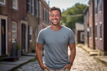 Wall Mural - Studio portrait photography of a happy boy in his 30s wearing a casual t-shirt against a historic colonial village background. With generative AI technology