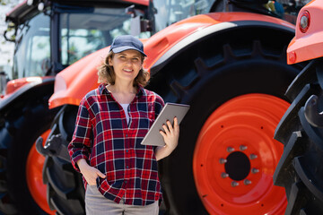 Poster - woman farmer with a digital tablet on the background of an agricultural tractors