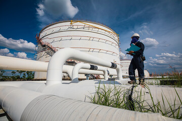 Wall Mural - Male worker inspection at steel long pipes and pipe elbow in tank oil station oil factory during refinery valve of visual check record pipeline oil and gas