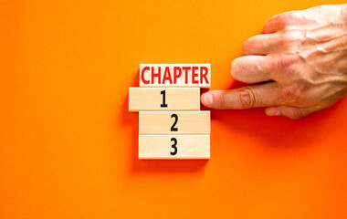 Wall Mural - Time to chapter 1 symbol. Concept word Chapter 1 2 3 on wooden block. Businessman hand. Beautiful orange table orange background. Business planning and time to chapter 1 concept. Copy space.