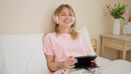 Sticker - Young blonde woman watching video sitting on bed at bedroom