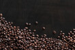 © Mariia - Roasted coffee beans on a wooden dark table, top view. Background of fragrant brown coffee beans scattered over the surface. copy space. Place for text