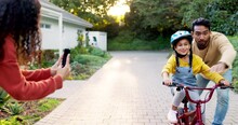 Mother, Father And Kid On Bike Learning In Driveway With Phone To Record Video, Photograph Or Family Support. Excited Parents Teaching Happy Girl On Bicycle With Mobile For Memory, Fun Games And Care