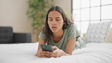 Poster - African american woman using smartphone lying on bed looking upset at bedroom