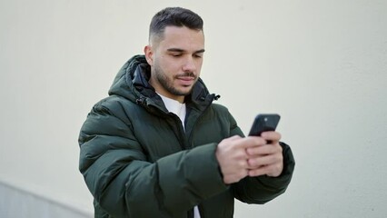 Wall Mural - Young hispanic man smiling confident using smartphone over isolated white background