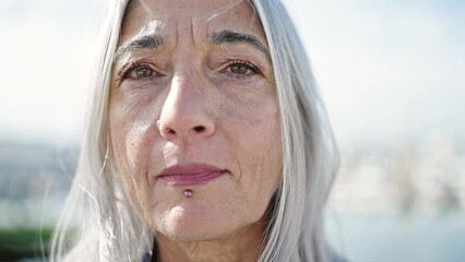 Poster - Middle age grey-haired woman standing with serious expression at seaside