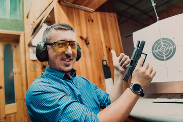 A man practices shooting a pistol in a shooting range while wearing protective headphones