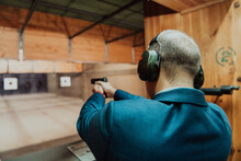 A Man Practices Shooting A Pistol In A Shooting Range While Wearing Protective Headphones
