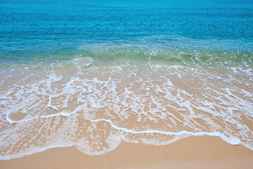 blue sea wave on the yellow sand with white bubbles