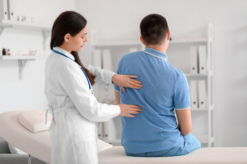 Canvas Print - Female doctor checking posture of young man in clinic