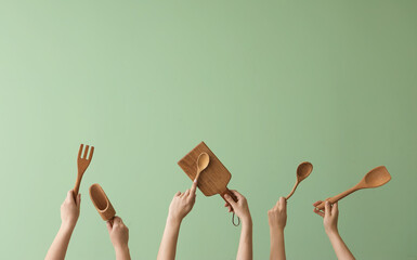 Women with wooden kitchen utensils on green background