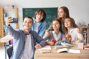 Canvas Print - Group of teenage students taking selfie at table in classroom