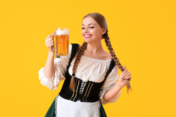 Beautiful Octoberfest waitress with beer on yellow background