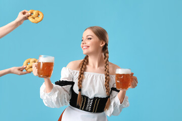 Beautiful Octoberfest waitress with beer and pretzels on blue background