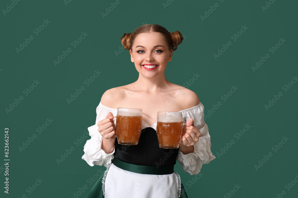 Beautiful Octoberfest waitress with beer on green background
