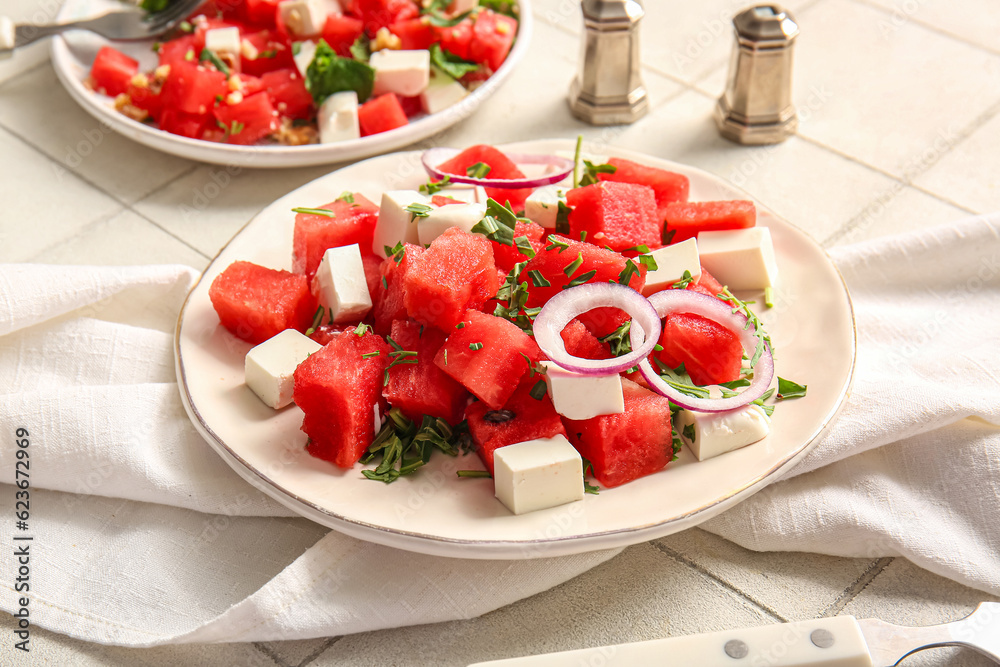 Plate of tasty watermelon salad on white tile background