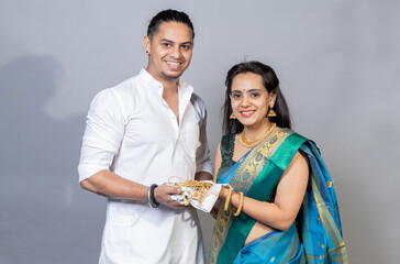 Indian couple holding gold jewelry, ornaments - Asset or Gold Loan concept.Indian couple looking towards the camera with jewellery’s’s in hand