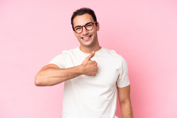 Wall Mural - Young caucasian man isolated on pink background giving a thumbs up gesture