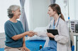 © Witoon - Beautiful smiling elderly female patient holding hands with professional female doctor at hospital bed