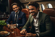 © Stavros - Two young businessmen on a flight in a private jet. They communicate, write out and rejoice in a successful deal.
