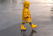 A Small Child Going Through Puddles On A Rainy Day.