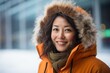© Anne Schaum - Portrait photography of a happy Chinese woman in her 40s wearing a warm parka against an abstract background