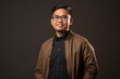© Anne Schaum - Portrait photography of a pleased Indonesian man in his 30s wearing a chic cardigan against an abstract background