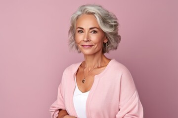 Wall Mural - Portrait of mature woman with grey hair looking at camera isolated on pink background