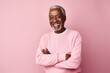 © Anne Schaum - Portrait of happy african american senior man with crossed arms looking at camera, standing against pink background