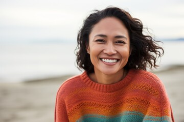 Wall Mural - Portrait of smiling young woman standing on beach and looking at camera