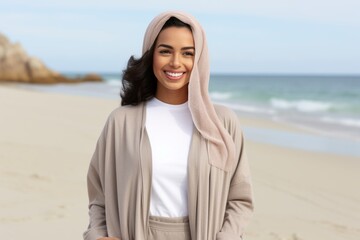 happy young woman in hooded coat on beach, summer vacation concept